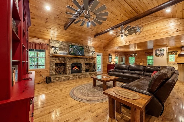 living room with wood ceiling, a stone fireplace, ceiling fan, and wood-type flooring