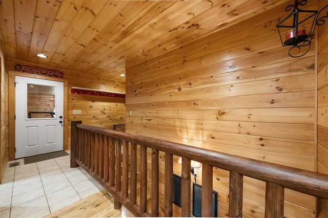 hallway with wooden walls, light tile patterned floors, and wood ceiling