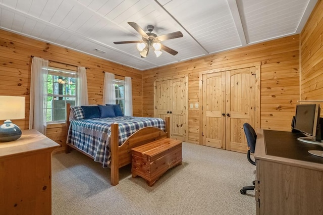 bedroom with ceiling fan, wood walls, and light carpet