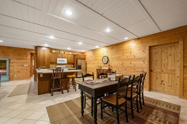 tiled dining space featuring wooden walls and wooden ceiling