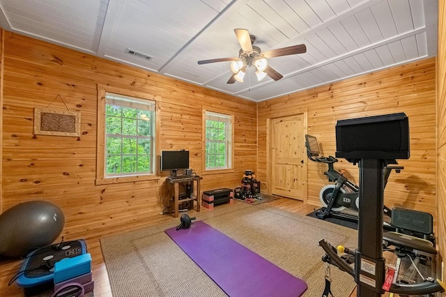 exercise area with wood walls, ceiling fan, and wood-type flooring