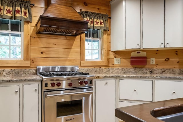 kitchen featuring plenty of natural light, white cabinetry, custom range hood, and high end stainless steel range oven