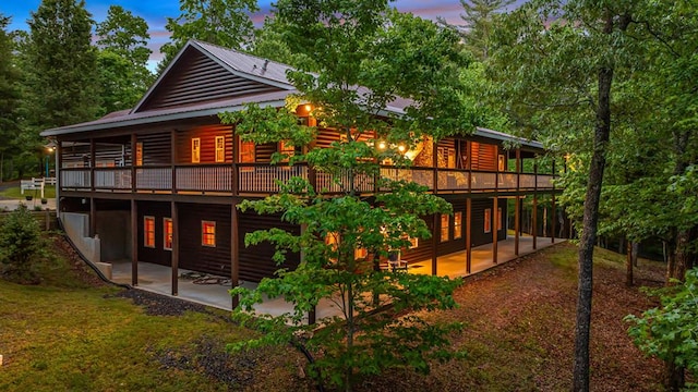 back house at dusk featuring a patio area and a wooden deck