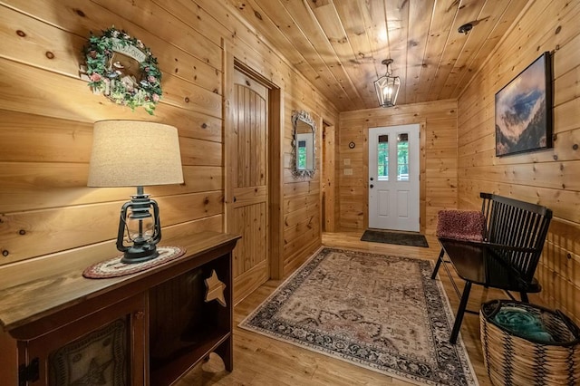 doorway featuring wood walls, wooden ceiling, a notable chandelier, and light wood-type flooring