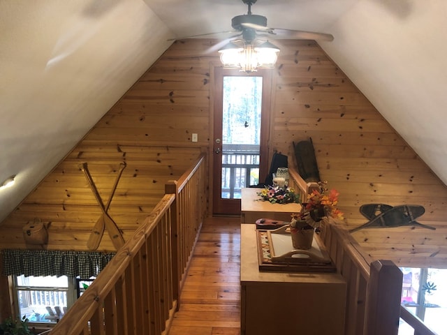 corridor with wooden walls, hardwood / wood-style floors, and vaulted ceiling