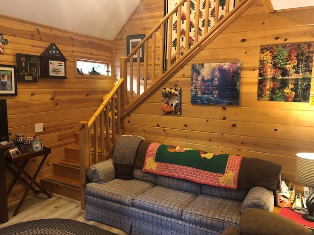 living room with wood walls, wood-type flooring, and vaulted ceiling