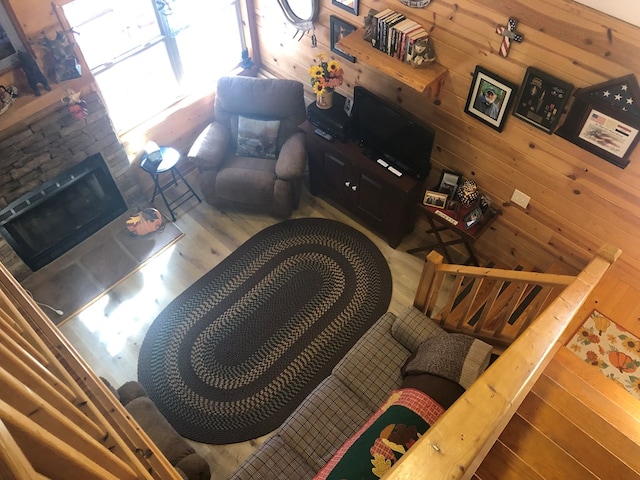 living room featuring a stone fireplace and wood walls