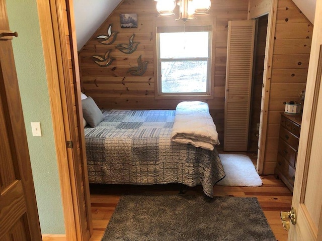 bedroom featuring wooden walls, vaulted ceiling, and hardwood / wood-style flooring