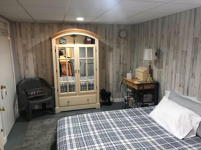 bedroom featuring a drop ceiling and wooden walls