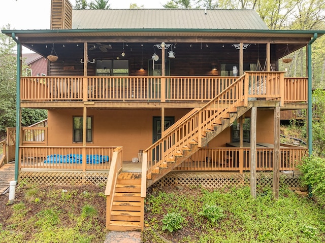 rear view of house with a chimney, a deck, metal roof, and stairs