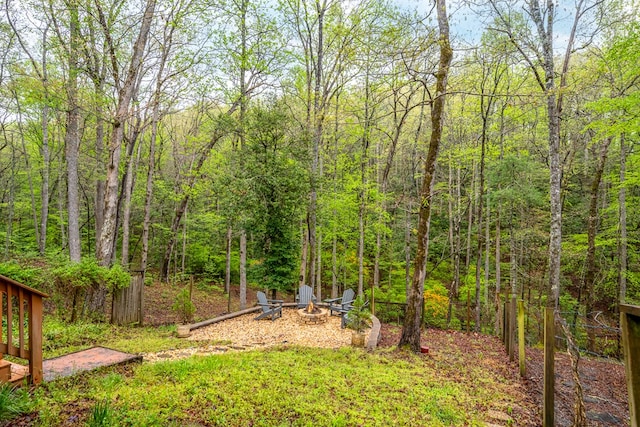 view of yard with an outdoor fire pit and a forest view