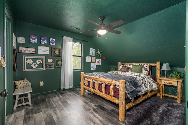 bedroom with wood finished floors, vaulted ceiling, visible vents, a ceiling fan, and a textured ceiling