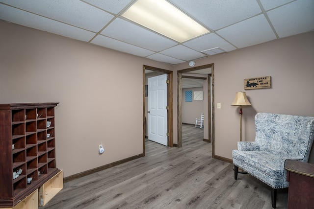living area with visible vents, a drop ceiling, wood finished floors, and baseboards