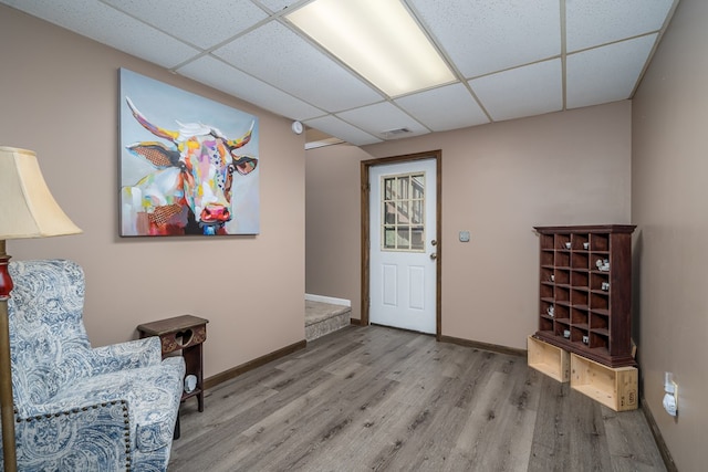 interior space featuring visible vents, a drop ceiling, wood finished floors, and baseboards