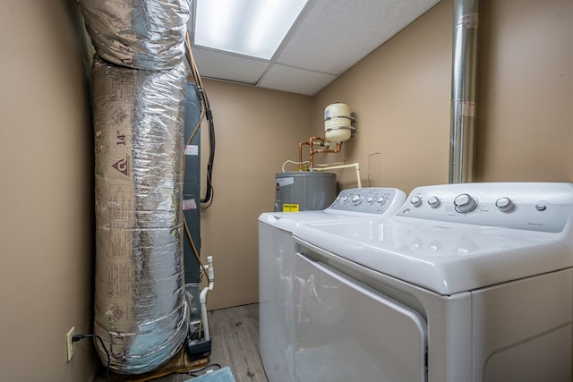 washroom with electric water heater, washing machine and clothes dryer, light wood finished floors, and laundry area