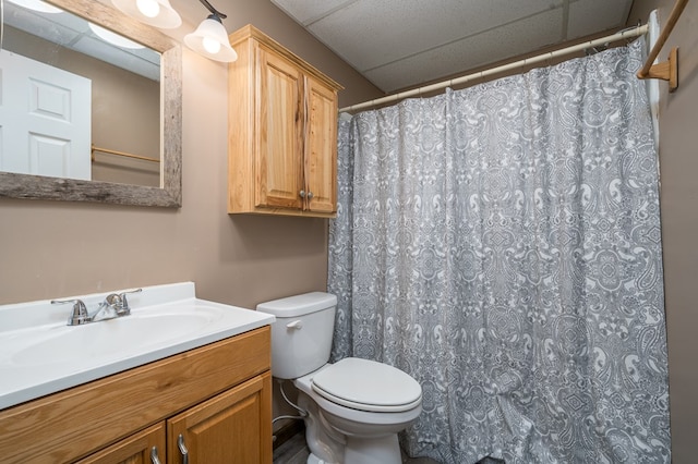 bathroom with toilet, curtained shower, a paneled ceiling, and vanity
