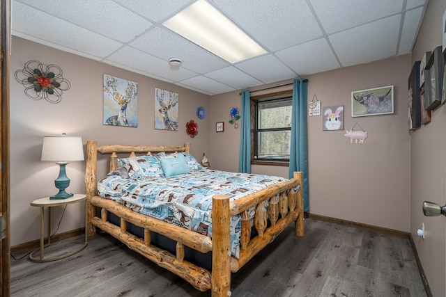 bedroom with light wood-style floors, a paneled ceiling, and baseboards