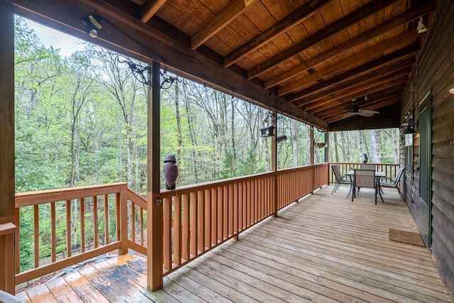 wooden deck with ceiling fan, outdoor dining space, and a forest view