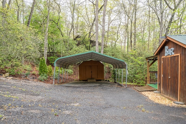 view of parking with a detached carport and a view of trees