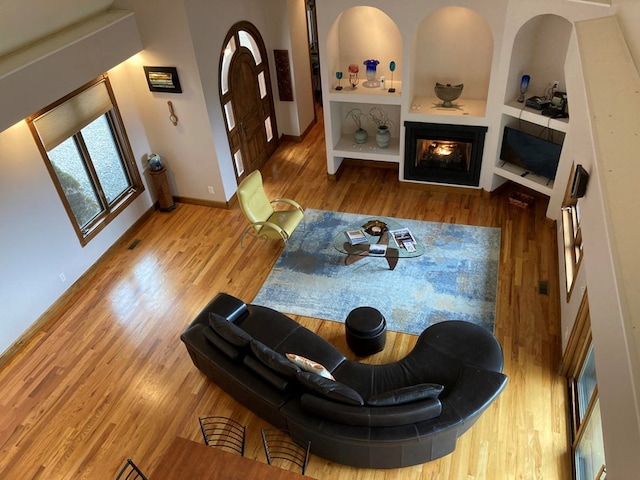 living room featuring built in features, a high ceiling, and light hardwood / wood-style floors