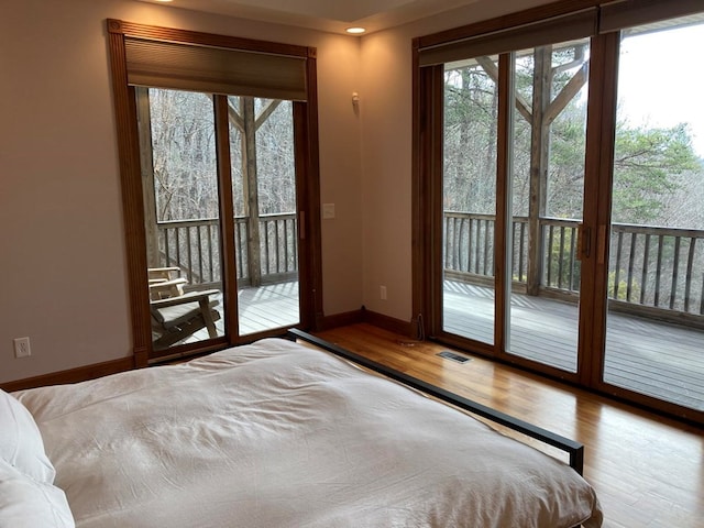 unfurnished bedroom with access to exterior and hardwood / wood-style flooring