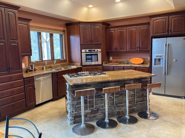 kitchen featuring light tile floors, a kitchen island, a kitchen breakfast bar, stainless steel appliances, and light stone countertops