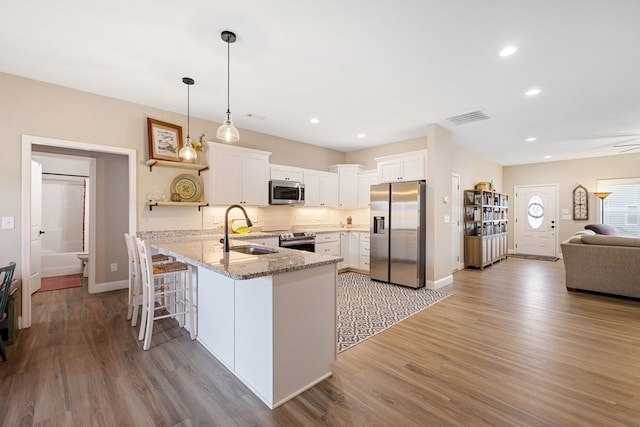 kitchen featuring pendant lighting, appliances with stainless steel finishes, visible vents, white cabinetry, and a sink