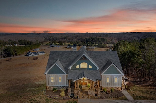 view of front of house featuring a forest view, roof with shingles, and board and batten siding