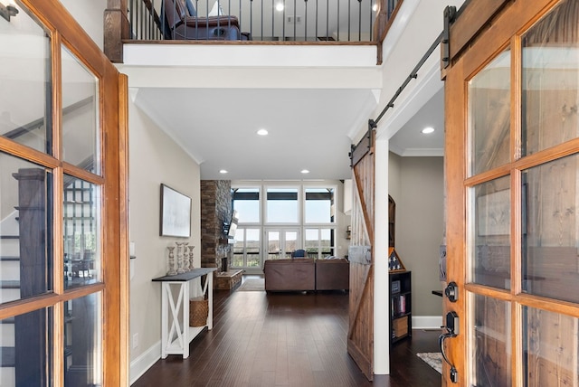 foyer entrance with baseboards, crown molding, a barn door, and dark wood-style flooring