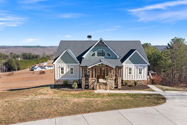 craftsman house with stone siding, board and batten siding, a front lawn, and roof with shingles