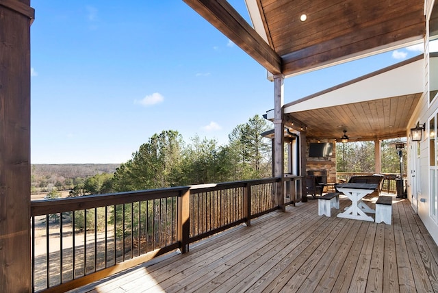 wooden terrace featuring an outdoor stone fireplace and a ceiling fan