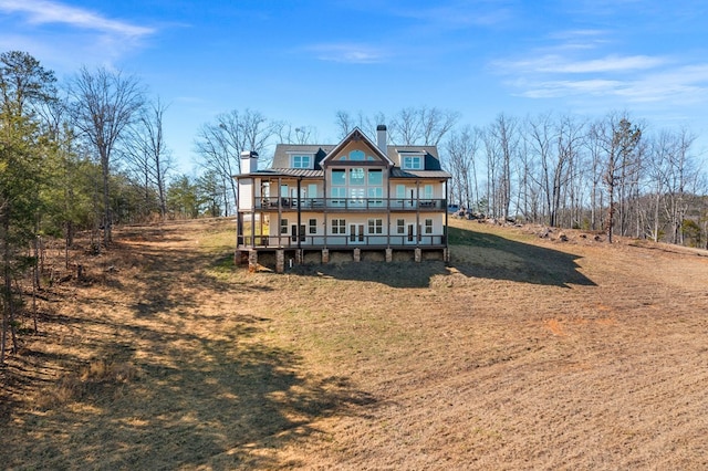 rear view of house with a chimney, a deck, and metal roof