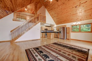 living room with light wood-type flooring, high vaulted ceiling, ceiling fan with notable chandelier, and wooden ceiling