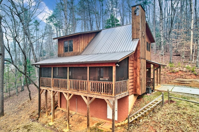 view of front of property with metal roof, a sunroom, and a chimney