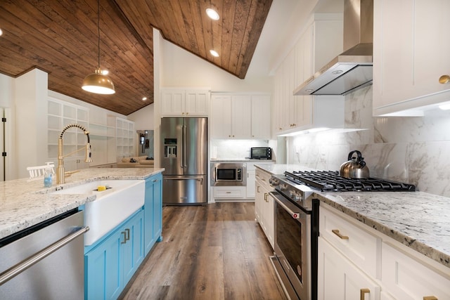 kitchen featuring blue cabinets, white cabinetry, premium appliances, and wall chimney exhaust hood