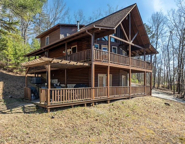 exterior space with faux log siding, a deck, and roof with shingles