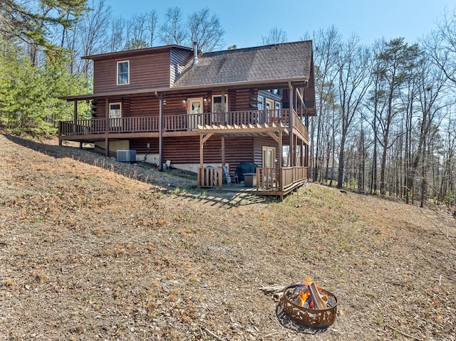 back of house with a wooden deck, a fire pit, roof with shingles, and cooling unit