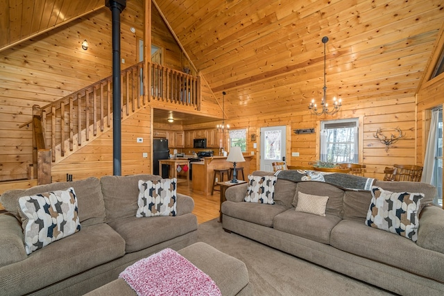 living area with a chandelier, wood walls, stairs, light wood-style flooring, and wooden ceiling