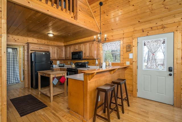 kitchen with light wood-style flooring, a peninsula, black appliances, and wooden ceiling