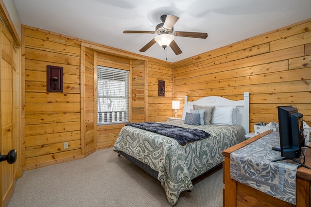 carpeted bedroom featuring wood walls and ceiling fan