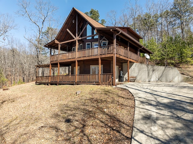 view of front of property with a wooden deck, concrete driveway, and log veneer siding