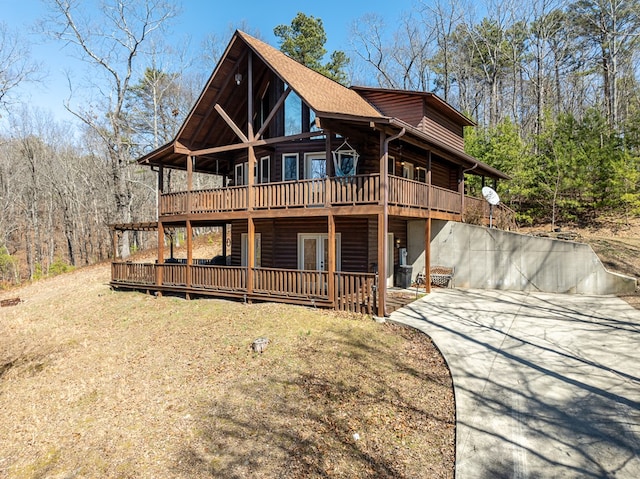 view of front of property featuring faux log siding, concrete driveway, and a deck