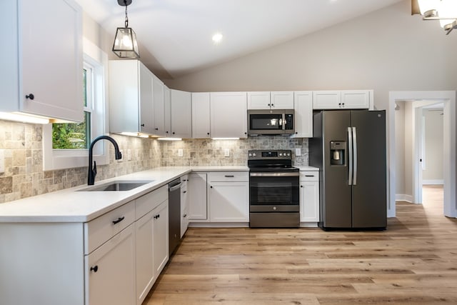 kitchen featuring appliances with stainless steel finishes, sink, pendant lighting, white cabinets, and light hardwood / wood-style flooring