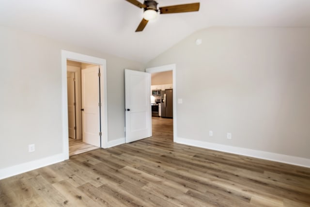 unfurnished bedroom with light hardwood / wood-style floors, stainless steel fridge with ice dispenser, vaulted ceiling, and ceiling fan