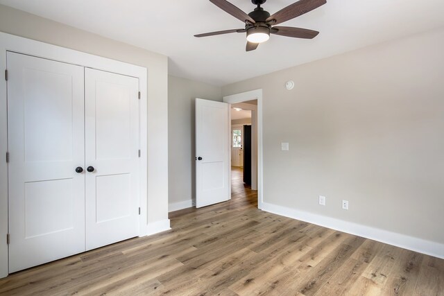 unfurnished bedroom featuring light hardwood / wood-style flooring, a closet, and ceiling fan