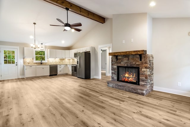 unfurnished living room with beamed ceiling, sink, light hardwood / wood-style flooring, and a fireplace