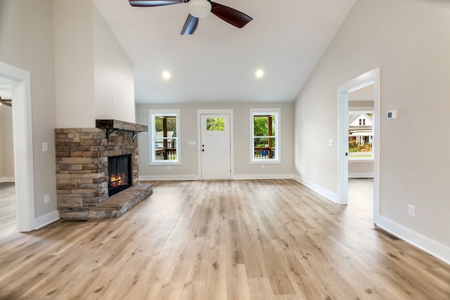 unfurnished living room with ceiling fan, high vaulted ceiling, a fireplace, and light wood-type flooring