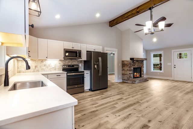 kitchen featuring white cabinets, appliances with stainless steel finishes, a fireplace, light hardwood / wood-style floors, and sink