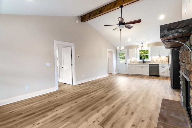 unfurnished living room featuring ceiling fan, light wood-type flooring, beamed ceiling, a stone fireplace, and sink