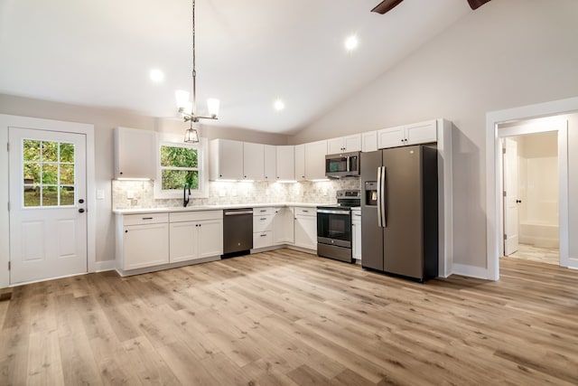 kitchen with appliances with stainless steel finishes, white cabinetry, high vaulted ceiling, light hardwood / wood-style flooring, and sink